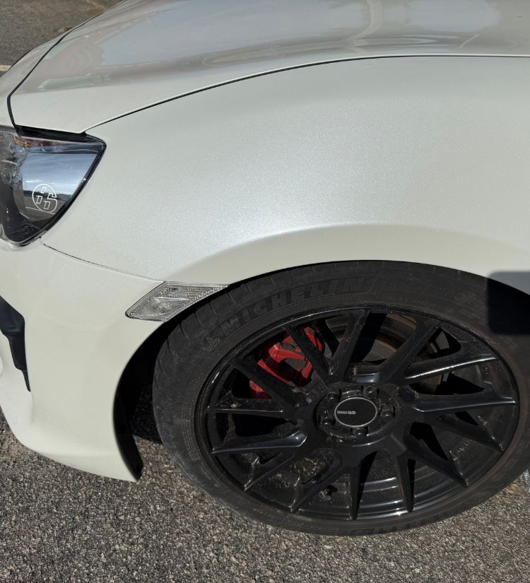 Smooth white fender on a sports car after dent and rust repair.