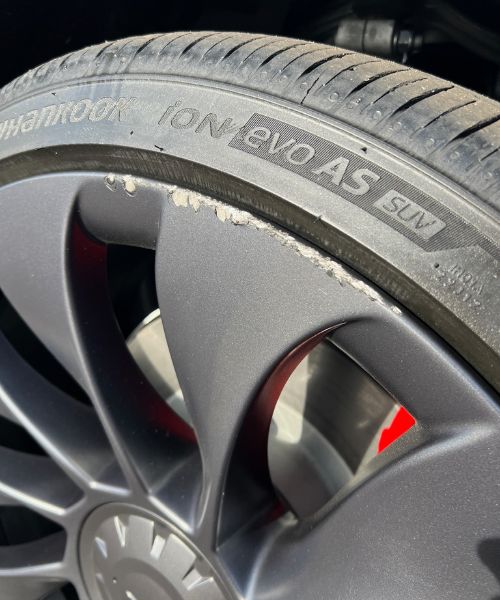 Scraped matte gray wheel rim with curb rash damage