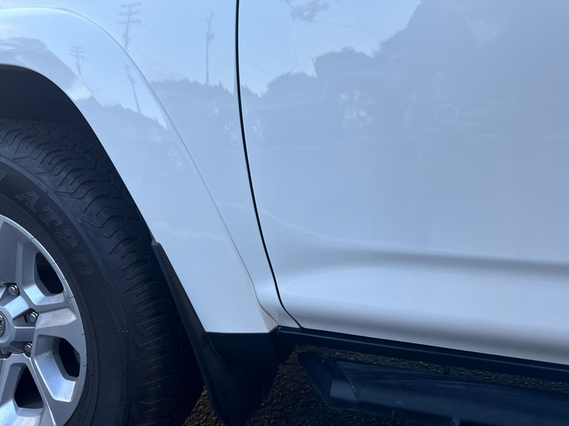 After: White vehicle rear passenger-side panel fully repaired with smooth, clean surface and no visible damage.