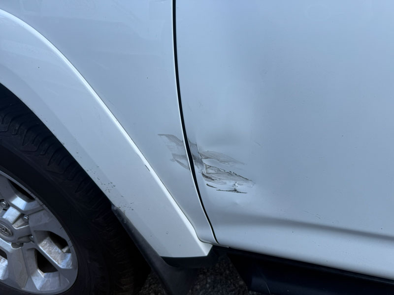 Before: White vehicle with visible scratches and dent on rear passenger-side panel above wheel.
