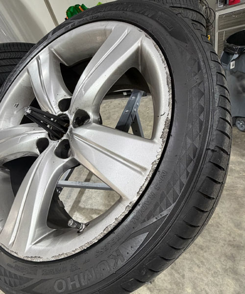Scraped matte gray wheel rim with curb rash damage